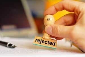 a hand holding a stamp saying rejected